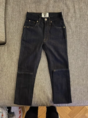 Mörkblå Tiger of Sweden jeans - Säljer ett par mörkblå jeans från Tiger of Sweden med raka ben och klassisk femficksdesign. Jeansen har kontrastsömmar och patch på bakfickan. Materialet är slitstarkt jeans och passformen är normal. Perfekta till en avslappnad stil. Bara testade en gång då de blev ändring. Storlek 24/32