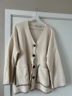 Zara kofta, med svarta sömmar - Vit kofta med svarta sömmar från Zara.              50 % bomull och 50 % polyester. 