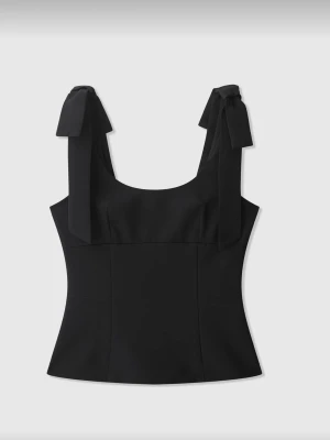 Svart korsettopp med knytband - Säljer en svart korsettopp med breda axelband som knyts i rosetter. Toppen har en figurnära passform och dragkedja i sidan för enkel på- och avtagning. Materialet känns slätt och stadigt, perfekt för att lyfta vilken outfit som helst.