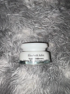 Elizabeth Arden fuktkräm - En lyxig vit fuktkräm från Elizabeth Arden, Visible Difference Refining Moisture Cream Complex. Kommer i en rund glasburk med vit plastlock. Perfekt för att återfukta huden och ge en fräsch känsla.