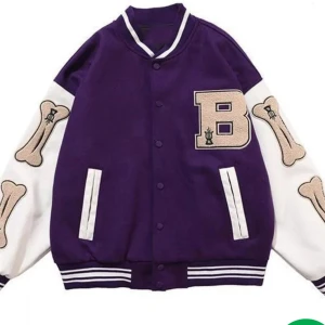 Lila och vit vintage bomberjacka indie - Snygg lila bomberjacka med vita ärmar och benmotiv. Jackan har en stor bokstav 'B' på bröstet och ribbade muddar i vitt och lila. Perfekt för en cool och avslappnad stil. Skadad: Har en liten röd fläck på höger arm. Storlek: L/XL. Välanvänd dock nt använd sen 2021, köpt på plick.