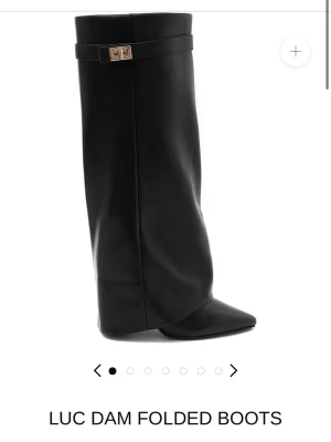 Svarta folded boots med spetsig tå storlek 38 - Säljer ett par svarta folded boots från lululia med spetsig tå och hög skaft. Skorna har en elegant gulddetalj vid kanten och är tillverkade i slätt skinn. Perfekt för dig som vill ha en unik och stilren look. Storlek 38 använd tre gånger. Inga defekter.