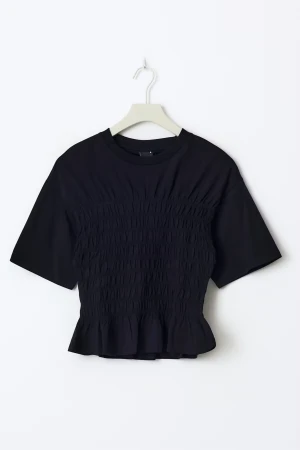 Svart blus med smock och volang - Svart blus med rund hals och korta ärmar. Toppen har smockad midja som ger en snygg form och avslutas med en liten volangkant nedtill. Materialet är mjukt och känns skönt mot huden. Perfekt att styla med jeans eller kjol för en cool look. Säljer tröjan då den inte kommit till användning 