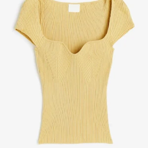 H&M ribbad gul topp  - Säljer en gul ribbad topp med korta ärmar och snygg v-ringad hals. Toppen har en figurnära passform och markerade sömmar framtill som ger en cool struktur. Perfekt för dig som gillar stilrena och trendiga plagg.
