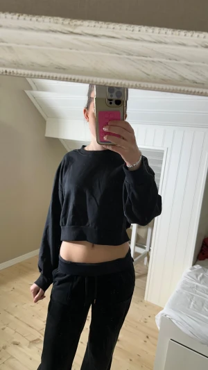 Svart croppad sweatshirt från H&M Divided - Svart croppad sweatshirt från H&M Divided med rund halsringning och långa ärmar. Det är en magtröja, storlek M men passar Xs och S. Tröjan är i mjuk bomullsblandning (60% bomull, 40% polyester) och har en relaxed fit med bred mudd nertill. Perfekt till chill dagar eller när du vill ha en enkel, clean look. Aldrig använd.