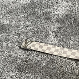 Bälte - Säljer nu ett as snyggt och stilrent bälte med ett vitt grått mönster. Bältet har ett silverigt L och V spänne.
