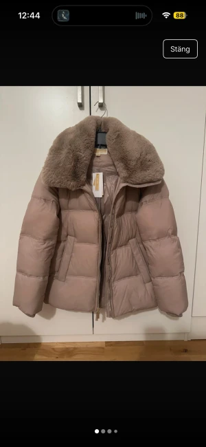 Champagnefärgad pufferjacka Michael Kors - Champagnefärgad pufferjacka från Michael Kors med fluffig fuskpäls på kragen och huva. Jackan har dragkedja framtill, två sidofickor och quiltad design. Nypris 3500🥰