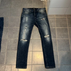 Replay Broken Edge slitna jeans W30 L32 - Tjenare säljer ett par mörkblå Replay Broken Edge jeans med slitningar och trasiga detaljer på benen. Jeansen har skinny passform, klassisk femficksdesign och snygg tvätt med ljusare partier. Perfekta för dig som gillar en edgy streetstil. Använd ca 2 gånger pågrund inte intresserad av dem 
