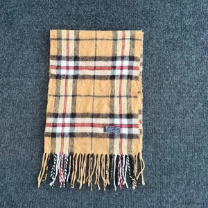 Burberry scarf - Burberry-scarf som är 100% äkta. Mindre defekter kan förekomma enligt bild men inget märkvärdigt då de är vintage. Snabb leverans och trygg handel då vi har 7 års erfarenhet i branschen. Vid frågor eller bud, skicka gärna ett meddelande. 1016