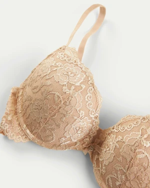 Beige spets push-up bh med rosett - Säljer en beige push-up bh med vacker spets och blommigt mönster. Bh:n har tunna axelband och en liten rosett mellan kuporna som extra detalj. Perfekt för dig som gillar romantisk och feminin stil. Använd fåtal gånger. Säljer endast för den här blivit för liten