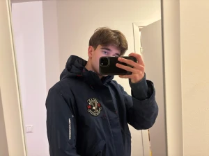 Mörkblå vindjacka Peak Performance - Snygg mörkblå vindjacka från Peak Performance med huva och coolt broderat emblem på bröstet. Jackan har dragkedja, snörning i huvan och ribbade muddar. Insidan har randigt foder och tryck. Perfekt för dig som gillar sportig stil och detaljer.