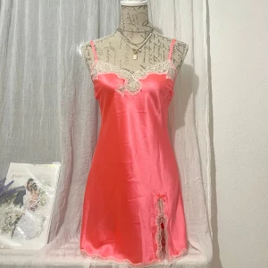 Orange satin nattlinne från Victoria’s Secret - Snygg nattlinne i orange satin med vacker glittrig  spets vid halsringning och slits. Storlek S, passar XS-S (34-36). Dockan är i storlek 36.