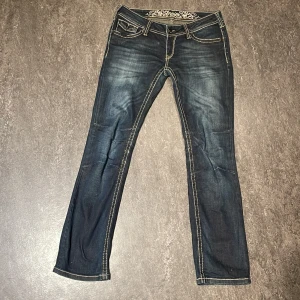 Mörkblå jeans från Soccx med broderi - Snygga mörkblå jeans från Soccx med kontrasterande ljusa sömmar och broderade detaljer på bakfickorna. Klassisk femficksmodell med låg midja och raka ben. Jeansen har coola knappar och ett broderat märke på insidan av linningen. Dom är dock lite korta när uppe vid midjan så jag tror att om man är över 168 ungefär så kommer dom sitta väldigt lågt💕