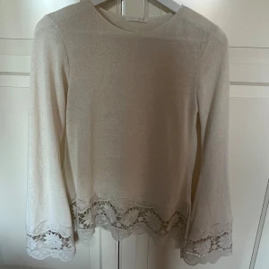 Vit stickad tröja med spets från Zara - Supersöt vit stickad tröja från Zara i storlek S. Tröjan har långa ärmar och fina spetsdetaljer med blommönster längst ner på ärmarna och nederkanten. Perfekt för dig som gillar en clean och feminin stil med extra detaljer.