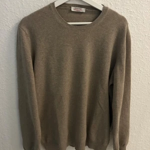Beige kashmirtröja Gran Sasso - Snygg beige kashmirtröja från Gran Sasso med rund hals och ribbade muddar. Tröjan har lång ärm och bruna mockadetaljer på armbågarna som ger en cool touch. Perfekt för dig som gillar stilrena och mjuka plagg. 