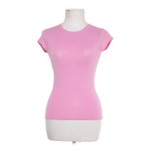 Rosa tight topp med kort ärm - Säljer en ljusrosa topp med rund hals och korta ärmar. Modellen är tight och figurnära, perfekt för dig som gillar en enkel och clean look. Materialet känns mjukt och stretchigt, vilket gör den skön att bära hela dagen.