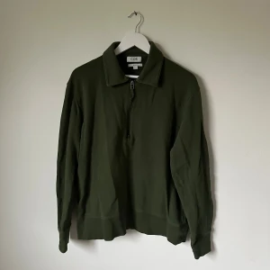 Mörkgrön half zip tröja från COS - Snygg mörkgrön tröja från COS i relaxed fit med krage och half zip framtill. Tillverkad i 100% bomull, perfekt för dig som gillar en chill och stilren look. Långärmad modell som passar till många olika outfits. 5I1