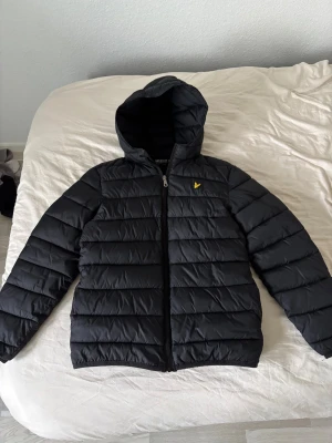 Lyle& scott vinter jacka - En svart lyle& scott vinter jacka som är från 12/13 år. Jackan är i bra skicka förutom att grejen som man hänger upp jackan med är sönder( som man ser på andra bilden).