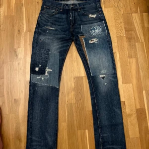  Polo Ralph Lauren jeans  - Säljer ett par mörkblå jeans från Polo Ralph Lauren med unika patchade detaljer och slitningar framtill. Jeansen har klassisk femficksdesign, raka ben och coola kontrastlappar i olika material. Tillverkade i 100% bomull för skön känsla och snygg look.  RRL, APC,Selvedge