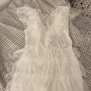 Vit spetsklänning från Bubbleroom - Superfin vit kort spetsklänning från Bubbleroom med v-ringning och volangdetaljer. En helt ny vit studentklänning som jag köpte i juni men aldrig använde. Prislappen sitter fortfarande kvar och den är helt oanvänd. Förpackningen har jag också kvar. Storlek 38 och den är från Bubbelroom och den är så fin. Nypris 899kr