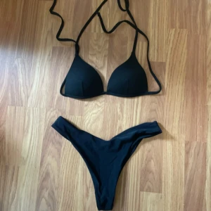 Svart bikini - Stilren svart bikini från shein, toppen är i xs och trosorna i s! Triangelformad överdel med knyt i nacken och ryggen, samt vadderade kupor. Matchande trosa med hög benskärning. Perfekt för stranden eller poolen, enkel och klassisk design.