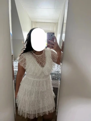 Vit studentklänning med spetsklänning och volanger - Superfin ny studentklänning från Bubbleroom i spets med  volanger och pärlknappar i ryggen. Klänningen har v-ringad front, korta ärmar och ett lager av transparent spets över hela. Perfekt för dig som söker klänning t studenten. Pris går att sänka såklart🙏🏼