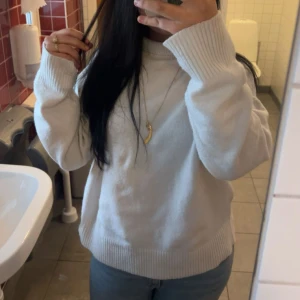 Vit stickad polotröja i loose fit - Säljer en vit stickad polotröja med loose passform och långa ärmar. Tröjan har breda ribbade muddar vid ärmslut och nederkant samt en hög krage som ger extra mysfaktor. Perfekt att matcha med jeans eller under en jacka för en chill look.