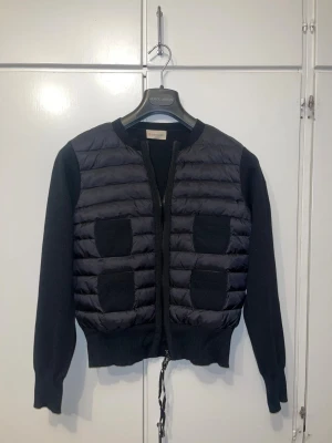 Svart cardigan jacka Moncler - Svart cardigan från moncler med quiltad front och stickade ärmar. Jackan är i väldigt fin skick och den är använd ett väldigt få tal gånger. Vid frågor och funderingar är det bara att höra av sig❤️. Priset är förhandlingsbart.
