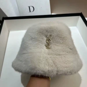 Lyxig pälsbucket hat från YSL - Säljer en supermjuk och fluffig bucket hat från YSL i ljusgrå päls med ikonisk guldfärgad YSL-logga framtill. Perfekt för dig som vill sticka ut med en exklusiv och trendig look. Hatten har rund form och bred kant.