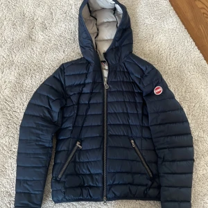 Mörkblå Colmar dunjacka med huva - Snygg mörkblå jacka från Colmar med huva och två dragkedjeförsedda fickor. 