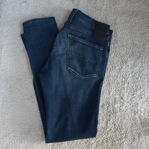 Replay anbass jeans - Säljer dessa replay anbass jeans då jag håller på att växa ur dem. Jeansen har en snygg indigo färg med fade och är stretchiga och bekväma. Inga defekter på jeansen, i princip nyskick förutom replay märket vid fickan som ser lite slitet ut. Skick 9/10