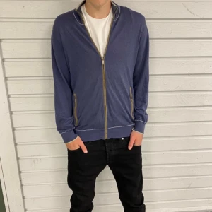 Blå kofta från Massimo Dutti, stl L - Snygg marinblå kofta från Massimo Dutti med hel dragkedja och kontrastfärgade mockadetaljer på armbågarna. Tröjan har hög krage, ribbade muddar och två fickor med dragkedja. Perfekt för lager-på-lager under kyliga dagar.