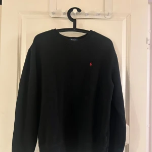 Svart tröja från Polo Ralph Lauren - Klassisk svart  tröja från Polo Ralph Lauren. Den passar bra till många outfits och är i ett bra skick. Storleken är XL i Barn så den sitter som en S/M vuxen storlek. Den var lite stor för mig när jag hade storlek S så skulle säga att den passar M bäst 