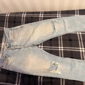 Ljusblå ripped jeans Jack & Jones 30/32 - Säljer ett par ljusblå jeans från Jack & Jones med snygga slitningar och hål på benen. Jeansen har klassisk femficksdesign, raka bakfickor och en relaxed vibe. Perfekta för dig som gillar en avslappnad och trendig look.
