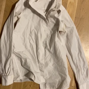 Vit skjorta från M&S School - Klassisk vit skjorta från M&S School med lång ärm och krage. Skjortan är tillverkad i bomull och har knappar framtill. Perfekt för en clean och stilren look.