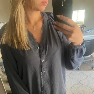 Gråblå blus från Vero Moda - Säljer en mörkgrå blus från Vero Moda med knappar framtill. Tycker väldigt mycket om den men aldrig kommit till användning. 