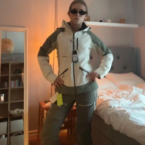 Skidset från Everest - Snygg vit och grönt skidset från Everest med huva och flera dragkedjeförsedda fickor. Settet har en sportig look, hög krage och justerbara detaljer.  Knappt använd och därför i väldigt bra skick! Storlek 36 i jacka och 38 i byxor. Säljer då jag letar efter andra typ av skidkläder!❤️‍🔥❤️‍🔥
