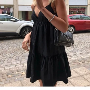 Svart volangklänning  - Svart kortklänning från Zara med tunna axelband, v-ringad och volang nedtill.
