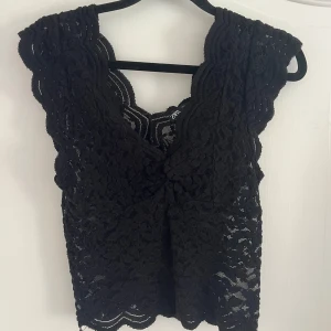 Svart spetsblus från Zara - Svart blus från Zara i storlek S, helt i spets med v-ringad hals och vågiga kanter. Funkar super med jeans eller kjol!