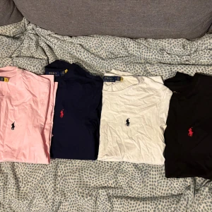 Polo Ralph Lauren t-shirt, flera färger - Fyra klassiska t-shirts från Polo Ralph Lauren i rosa, marinblå, vit och svart. Alla har kort ärm, rund hals och den ikoniska broderade loggan på bröstet. Tillverkade i mjuk bomull för en skön och stilren look. Styckpris 250 eller alla 4 för 80