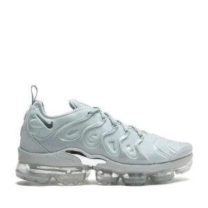 Nike Air Vapormax Plus ljusgrå sneakers - Nike Air Vapormax Plus sneakers i en clean ljusgrå färg med futuristisk design och genomskinlig sula. Ovandelen har vågiga detaljer och diskret Swoosh-logga på sidan. Skorna har snörning och är tillverkade i syntetmaterial för en modern vibe.