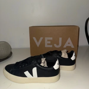 Svarta Veja sneakers i skinn - Snygga svarta Veja sneakers i skinn med vita detaljer och beige sula. Klassisk låg modell med snörning och rund tå. Ikoniskt V på sidan och Veja-logga på hälen. Perfekta för dig som gillar stilrena och trendiga sneakers. (Liten defekt sista två bilderna som tillkom när jag försökte skicka tillbaka de i boxen, att de tagit emot på något sätt)