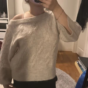 Beige kabelstickad tröja Gina oversize  - Supermysig beige kabelstickad tröja från H&M med bred ribbad kant och offshoulder-look. Tröjan har lång ärm och en loose passform som ger en chill vibe. Perfekt för lager på lager under höst och vinter.