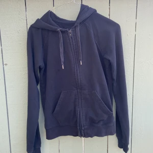 Svart hoodie med dragkedja XS - Svart hoodie från C i ekologisk bomull. Klassisk modell med huva, dragsko och hel dragkedja framtill. Mjukt material och två stora fickor framtill. Perfekt för chill dagar eller när du vill ha en enkel och stilren look.knappt använd är som helt ny. Hämtas i norsborg botkyrka.