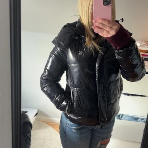 Svart pufferjacka från Calvin Klein Jeans - Säljer en svart, glansig pufferjacka från Calvin Klein. Säljer då den inte kommer till användning längre 🥰
