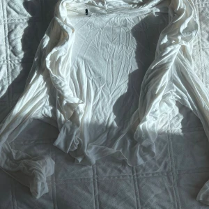 Vit tunn kofta i mjukt material - Säljer en supermjuk och tunn vit kofta med långa ärmar. Koftan är öppen framtill och har ett flowy fall, perfekt att slänga över en topp eller klänning. Materialet känns svalt och lätt, vilket gör den skön att bära under vår och sommar.