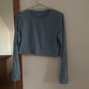 Blå croppad långärmad topp 157 - Säljer en enkel och stilren ljusblå croppad långärmad topp från 157. Toppen har rund halsringning och är tillverkad i mjuk bomull, perfekt att matcha med jeans eller kjol för en chill look.
