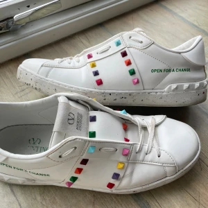 Valentino Garavani Rockstud  - Säljer ett par vita Valentino Garavani Rockstud sneakers med färgglada nitar i rött, lila, grönt, rosa, orange och blått. Skorna är gjorda i premium läder och nypris ligger på runt 7500 kr. Kontakta mig vid minsta fråga eller fundering!😇