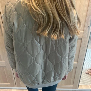 Beige quiltad bomberjacka - Snygg höstjacka i quiltat material!! Jackan är oversized i storlek xs och lite glansig i materialet. PRISLAPP kvar!