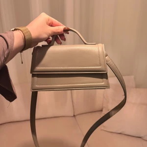 Ljusgrå axelväska med handtag - Snygg beige axelväska från Gina tricot med stilren, boxig form och ett praktiskt handtag upptill. Aldrig använd✨